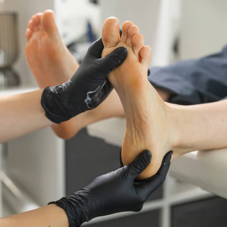 Treatment of foot pain by podiatrist with gloves.
