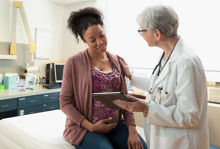 Pregnant woman consulting with doctor in clinic.