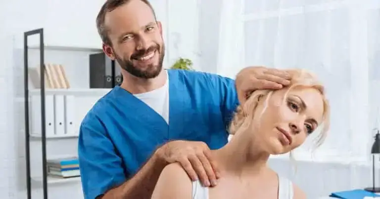 Chiropractor providing neck and shoulder adjustment to a female patient in a clinical setting.