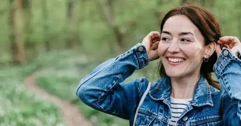 Woman enjoying outdoor walk in lush green forest, embracing nature's health benefits.