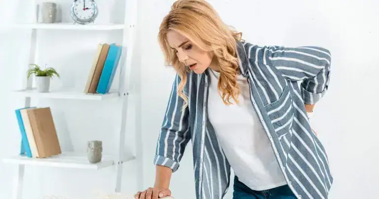 Woman experiencing back pain, demonstrating the importance of movement for relief and recovery.