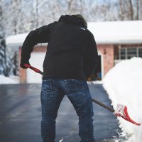 Man shoveling snow on his driveway in the winter Man shoveling snow on his driveway in the winter