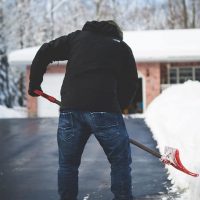 Man shoveling snow on his driveway in the winter Shoveling snow in front of a house during winter in Canada.